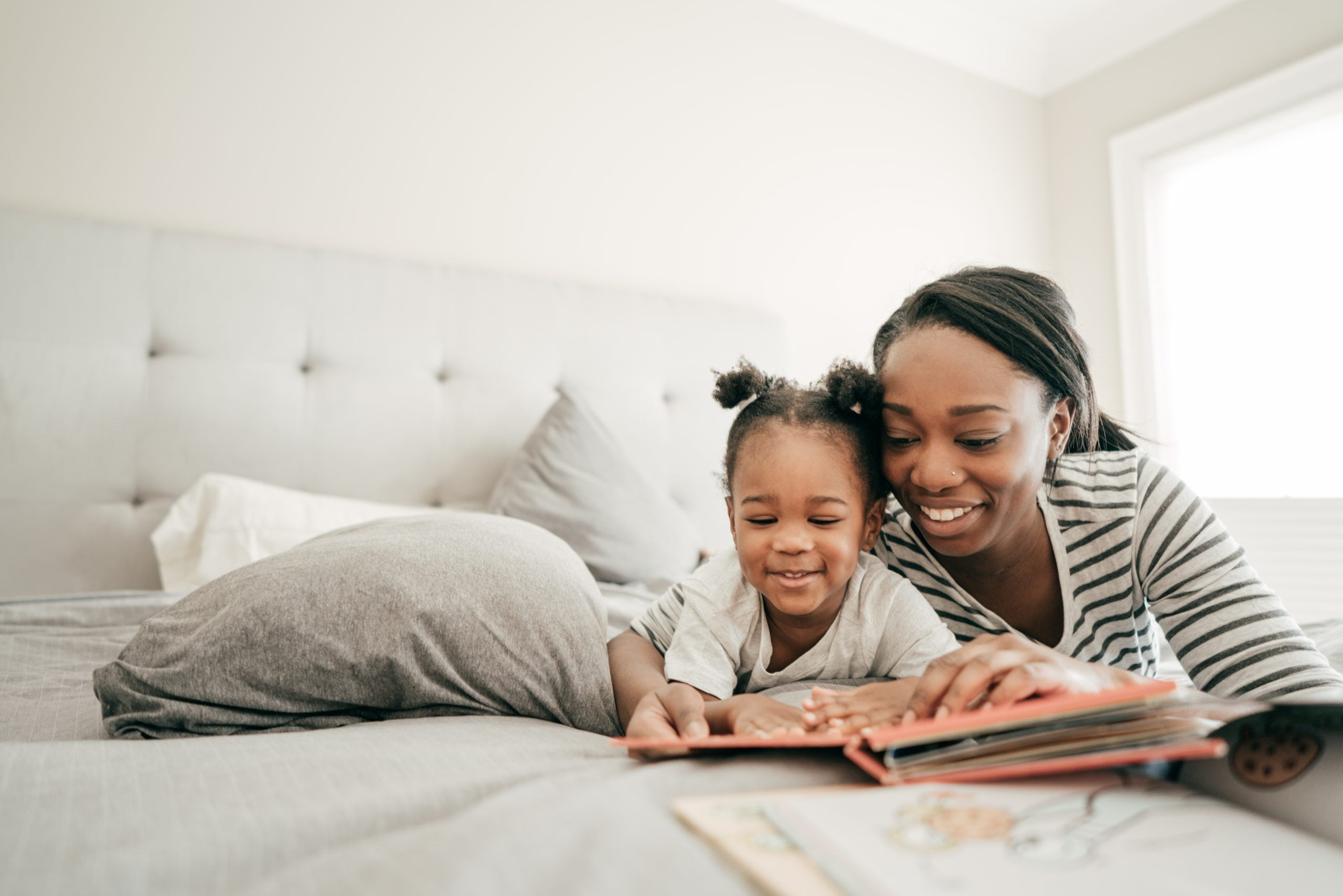 A mother and daughter doing homework in bed.